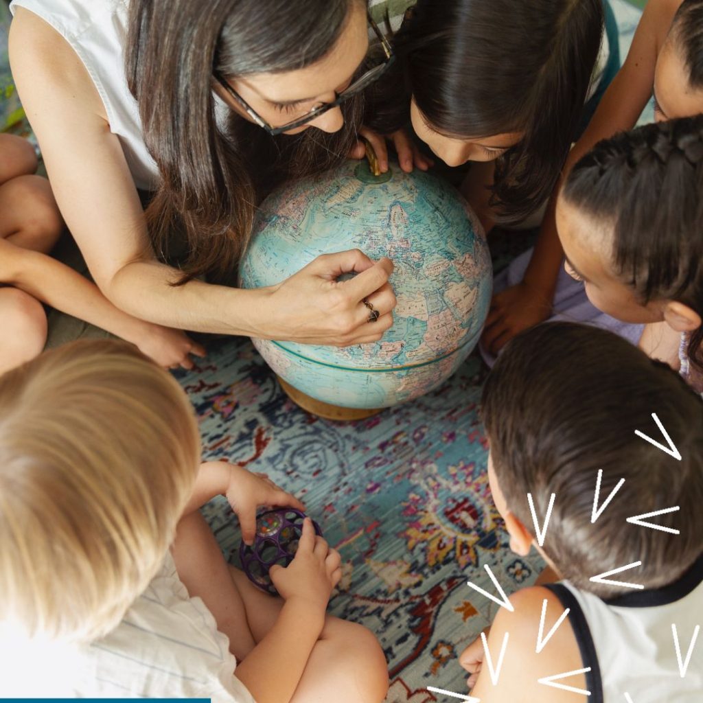 A woman surrounded by children, all looking at a globe.