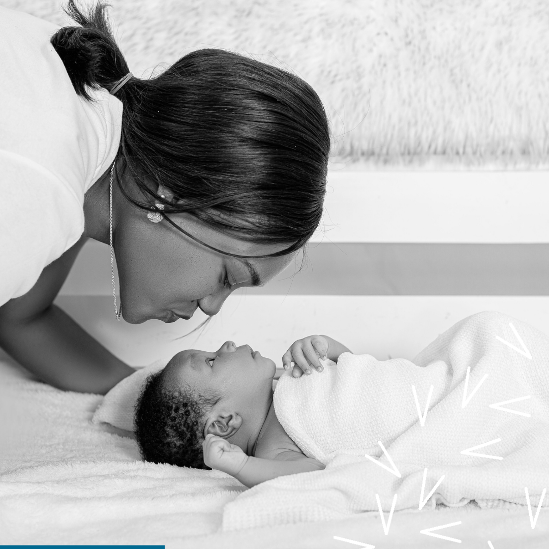 A mother lovingly gazes at her newborn baby wrapped in a soft blanket. The baby gazes back.